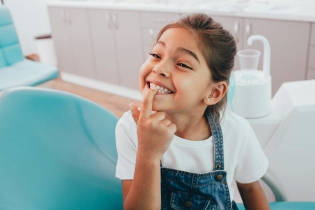 child patient showing her teeth to a dentist