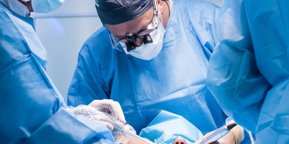 A male dentist in uniform perform dental implantation operation