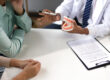 Man with toothache consults with doctor in examination room. Dentist demonstrating an anatomical model of the human jaw while explaining treatment options to a patient in a dental clinic.