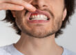 Handsome man touch mouth with hand, with painful expression of toothache