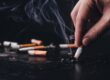 Person holding a cigarette representing the link between smoking and periodontal disease