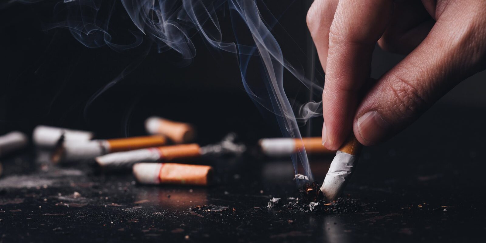 image-1786096837776 Person holding a cigarette representing the link between smoking and periodontal disease