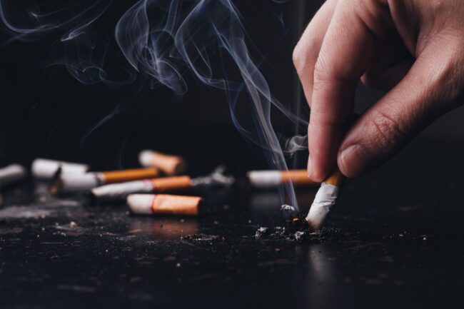 image-1786096837776 Person holding a cigarette representing the link between smoking and periodontal disease